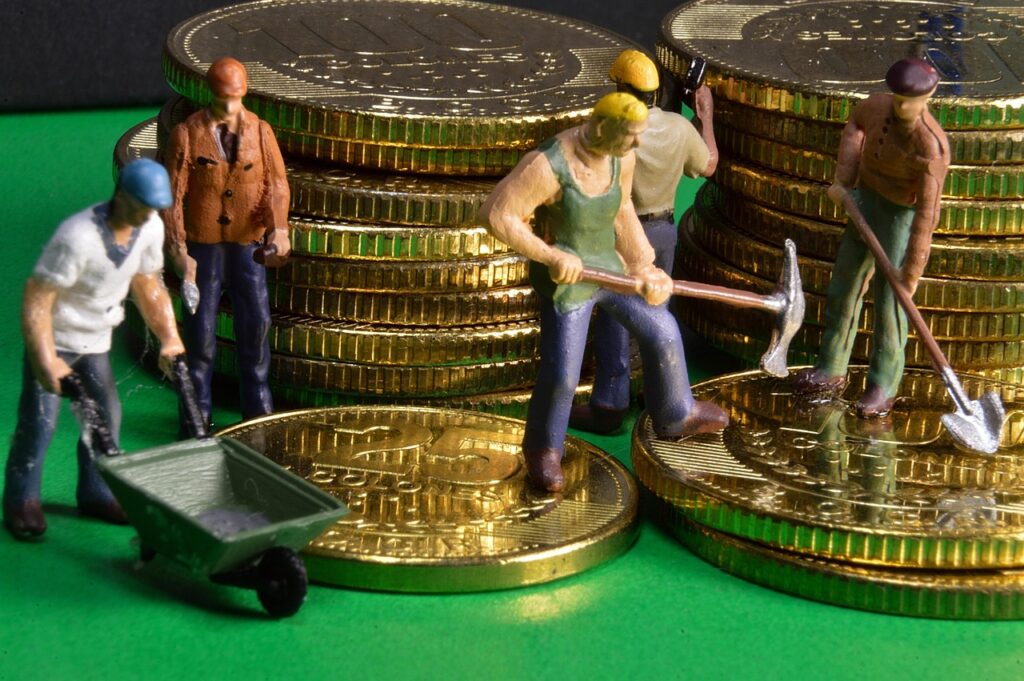 a stack of gold coins and mini working men figurines, like a financial team